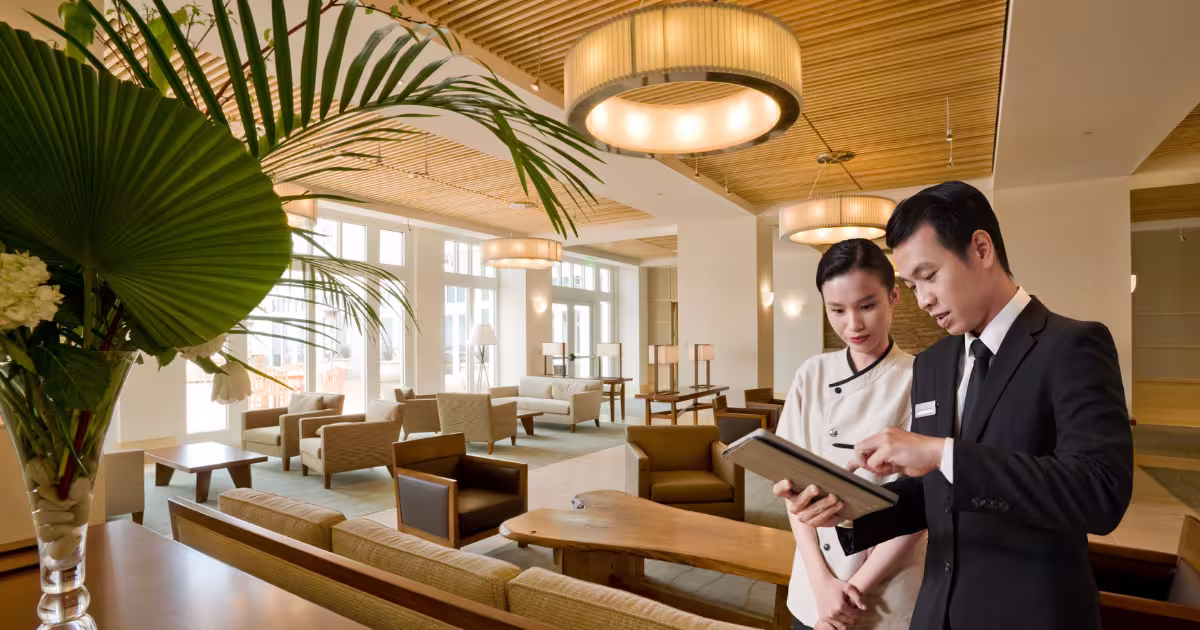 Hotel manager reviewing standards on a tablet with a team member in a hotel lobby